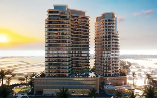 Two modern high-rise buildings, prominently featured by ALIYAS Real Estate, boast numerous balconies and are nestled among palm trees. They overlook a marina and beach where the sun sets on the horizon, casting a warm glow over this idyllic scene.